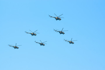 Military helicopters maneuvers in the blue sky. Group combat helicopters in flight during a military demonstration