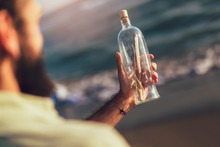 Man By The Beach With Message In A Bottle