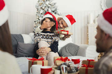 Wall Mural - Handsome man surprising girl with Christmas present