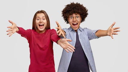 Photo of amazed mixed race women best friends give warm hug at camera, notice close people in front, express positive emotions and feelings, isolated over white background. Come here, please!
