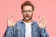 © wayhome.studio  - Calm down, please! Handsome unshaven Caucasian man keeps palms in front, asks to leave him in peace and not interrupt, has indignant facial expression, poses against pink background, gestures indoor