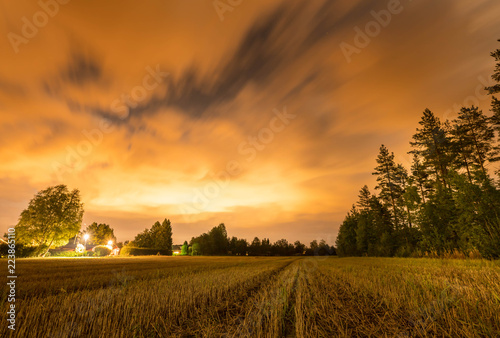 Fotografía long exposure night photo of forest, harvested field and dark heavy clouds at sw