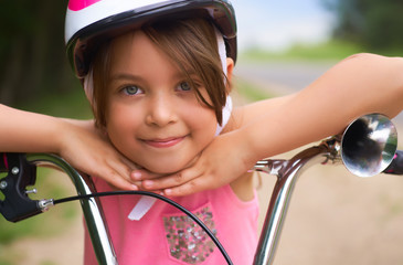 Close-up of a little girl's face on bike looking at camera and smiling