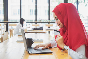 Fototapete - attractive female Arabic holding credit card and using laptop for shopping or payment online.