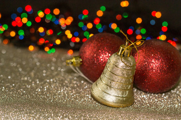 Christmas and new year red decoration isolated on golden and colorful bokeh background. Christmas toys: bell and two red balls.