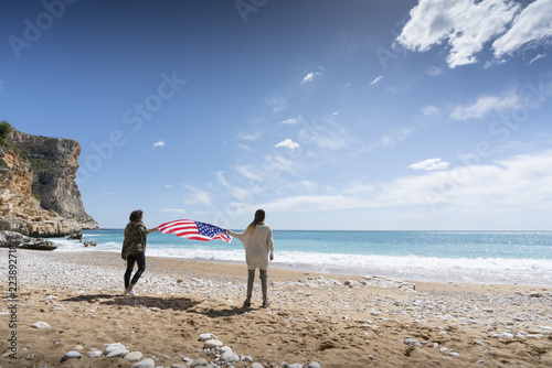 Photographie Two girls holding United states of America flag in beach