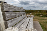 Fototapeta Most - Closeup empty wooden bench under cloudy sky, Peggy's Cove, Canada.