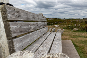  Closeup empty wooden bench under cloudy sky, Peggy's Cove, Canada.
