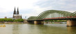 Panoramic view of Cologne Cathedral and Hohenzollern Bridge with train passing, Cologne, Germany. Banner panorama.