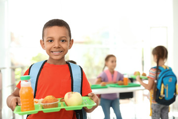 African-American boy holding tray with healthy food at school canteen