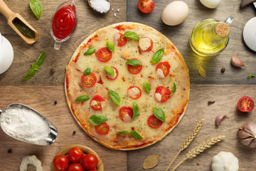 pizza and food ingredients at wooden table