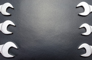 Metal flat wrenches lying on a black table, top view, flat lay.