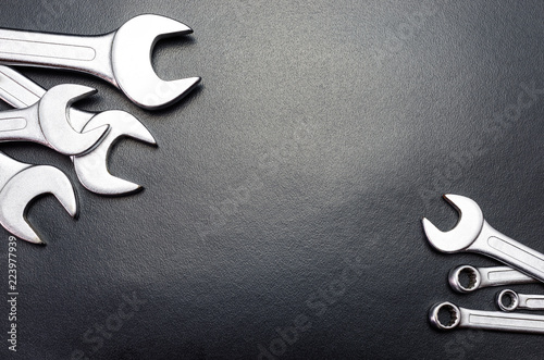 Fotografie, Obraz Metal flat wrenches lying on a black table, top view, flat lay.