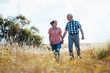 © Kzenon - Senior couple walking over meadow holding each others hands still in love