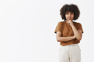 Wall Mural - studio shot of thoughtful suspicious and doubtful cute african american teenage girl with afro hairs