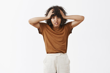 Wall Mural - studio shot of silly and timid good-looking dark-skinned female student being upset and troubled hav