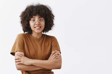 Wall Mural - waist-up shot of shy and silly dark-skinned teenage female in transparent glasses and trendy brown t