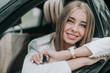 © Yakobchuk Olena - Portrait of cheerful businesswoman with attractive smile holding key while looking at camera. She situating in car