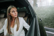 © Yakobchuk Olena - Portrait of serene female employer watching at street while going in cozy car cabin on backseat. Orderly lady moving to labor concept