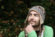 © Gargonia - portrait of a young bearded smiling man in warm hat on autumn forest background. fall mood concept