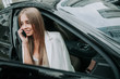 © Yakobchuk Olena - Portrait of happy pretty female telling on mobile while looking from opened window of contemporary car. Satisfied lady during communication on gadget in vehicle concept