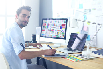 Fototapete - Portrait of young designer sitting at graphic studio in front of laptop and computer while working online.