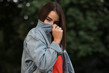 Wall Mural - Woman hiding her face behind a denim jacket in a park