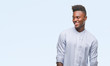 © Krakenimages.com - Young african american man over isolated background looking away to side with smile on face, natural expression. Laughing confident.
