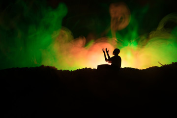 Wall Mural - Silhouette of praying Muslim man on toned foggy background. Ramadan Kareem background. Muslim Eid holiday decoration. Praying people religion concept.