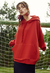 Wall Mural - Gorgeous brunette woman in fashion red hoodie on sports field