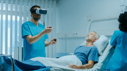 Wall Mural - Doctor Wearing Virtual Reality Headset and Holding Joysticks Cures Senior Patient who is Lying in Bed. Most Advanced Technologies Used in Futuristic Hospital Ward.