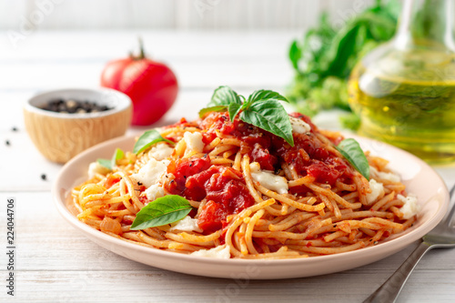 Fotografía Spaghetti pasta with tomato sauce, mozzarella cheese and fresh basil in plate on white wooden background