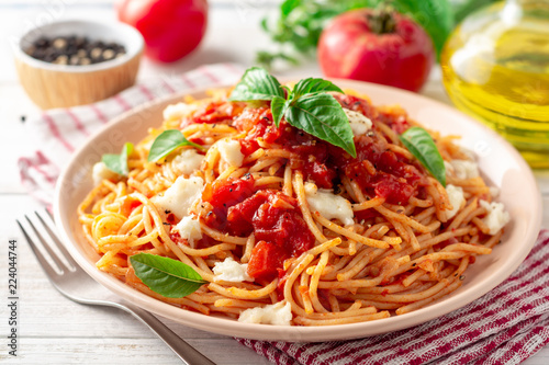 Fotografía Spaghetti pasta with tomato sauce, mozzarella cheese and fresh basil in plate on white wooden background