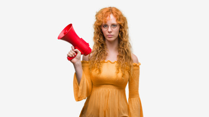 Sticker - Young redhead woman holding megaphone with a confident expression on smart face thinking serious