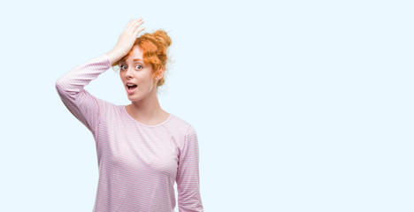 Wall Mural - Young redhead woman surprised with hand on head for mistake, remember error. Forgot, bad memory concept.