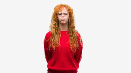 Poster - Young redhead woman wearing red sweater puffing cheeks with funny face. Mouth inflated with air, crazy expression.