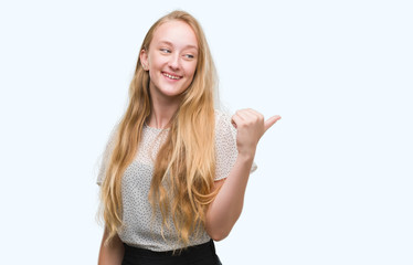 Poster - Blonde teenager woman wearing moles shirt smiling with happy face looking and pointing to the side with thumb up.