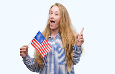 Poster - blonde teenager woman holding flag of united states of america surprised with an idea or question po