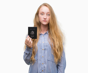 Sticker - Blonde teenager woman holding passport of Unites States of America with a confident expression on smart face thinking serious