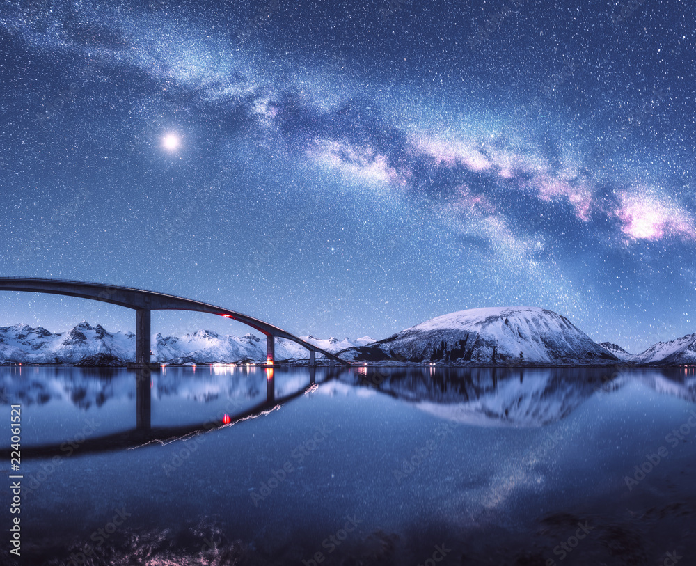 Bridge and starry sky with Milky Way over snow covered mountains ...