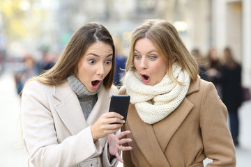 Poster - Surprised women reading phone content in winter in the street