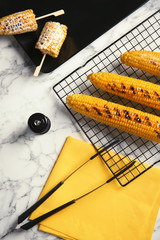 Cooling rack with grilled corn cobs on marble background, top view