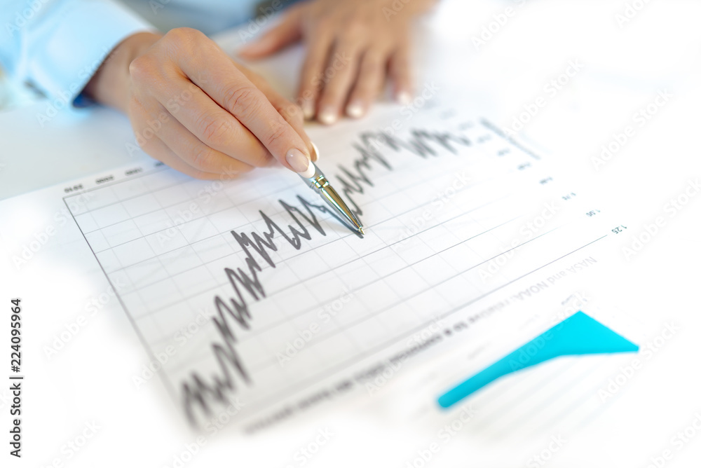 Anlagegeschäft, Finanzauswertung, Frauenhand mit Kugelschreiber