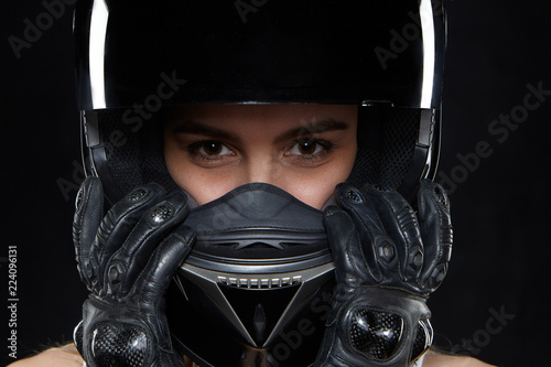 Fotomural Beautiful young woman in black leather gloves and protective motorbike helmet in studio