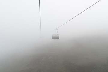 Poster - empty chairlift and cable in a bleak and foggy mountain landscape in the early autumn in a ski resort in Switzerland