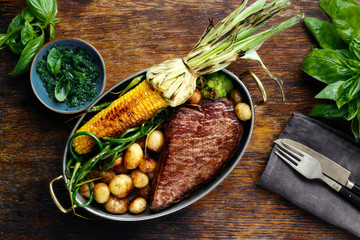 Wall Mural - juicy beef steak in frying pan with vegetables top view