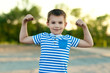 Young Teenager Boy Showing his body muscles biceps in park