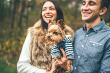 Pretty couple with little yorkshire terrier walking in the forest.