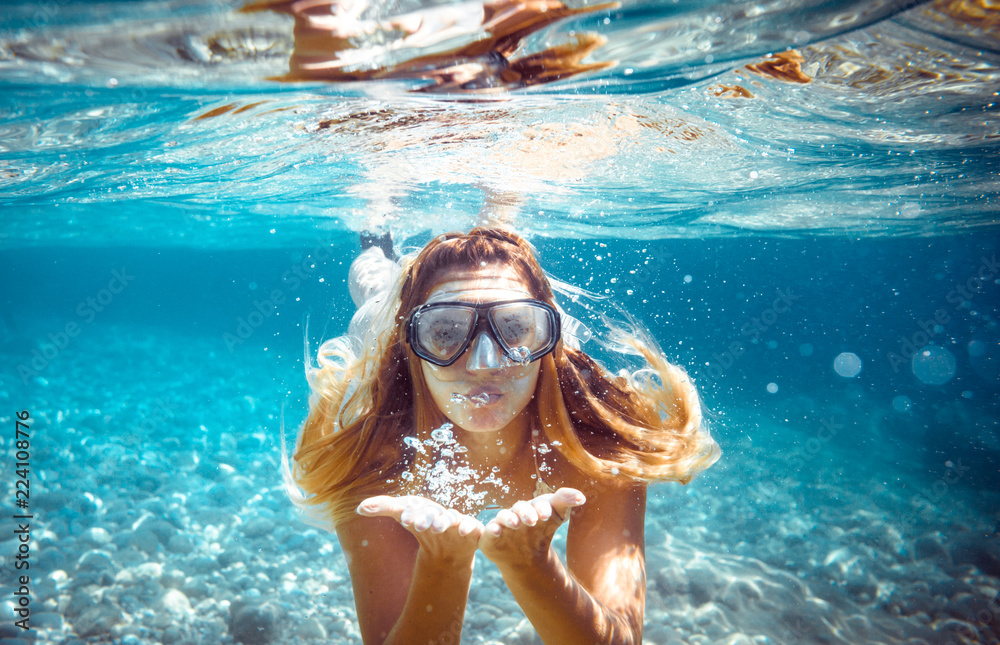 Snorkeling woman blowing a kiss underwater in the tropical sea - obrazy, fototapety, plakaty 