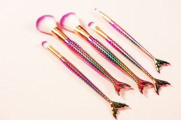 Set of mermaid tail make-up brushes. Make up tools on pastel backg